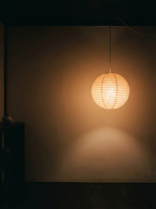 A paper lantern glowing against a plain wall