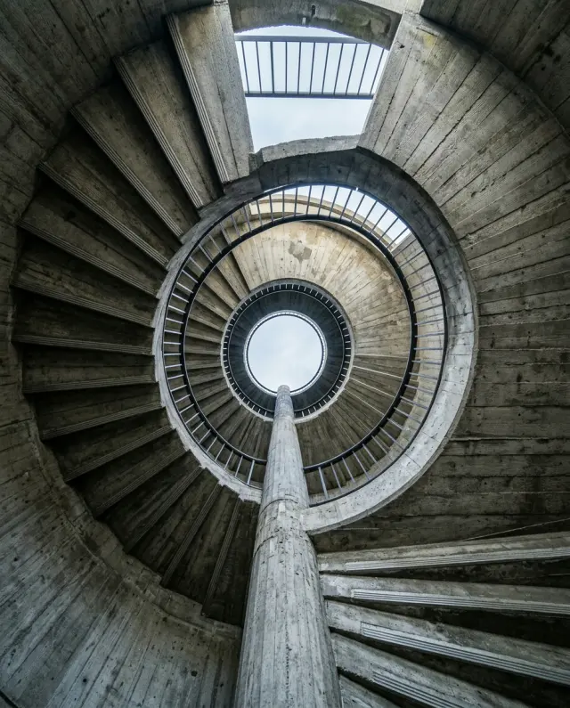 A spiral concrete stairwell seen from below